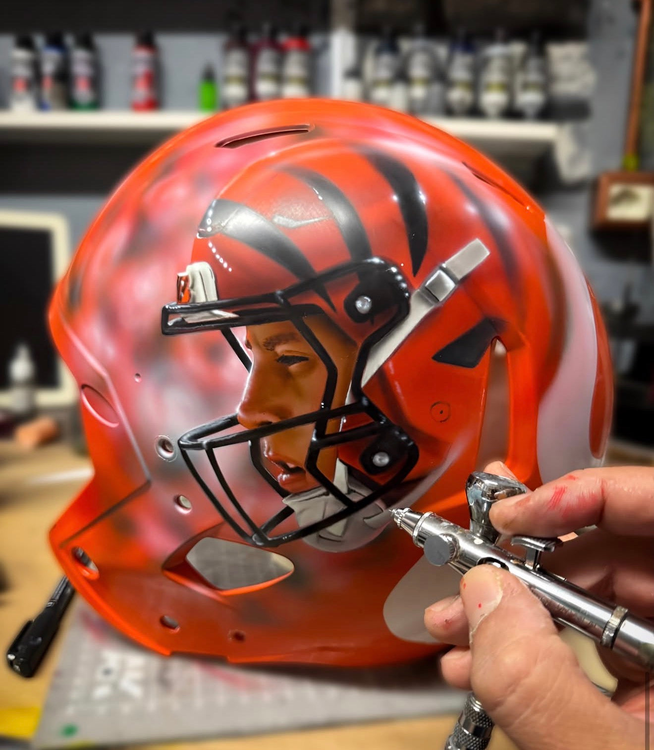 Grizzly Airbrush creating a player portrait on an orange Cincinnati Bengals helmet